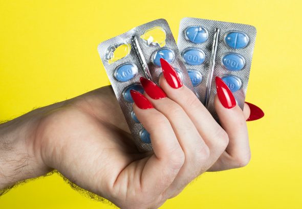 a woman's hand holding two contraptions in front of a yellow background