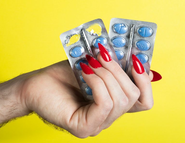 a woman's hand holding two contraptions in front of a yellow background